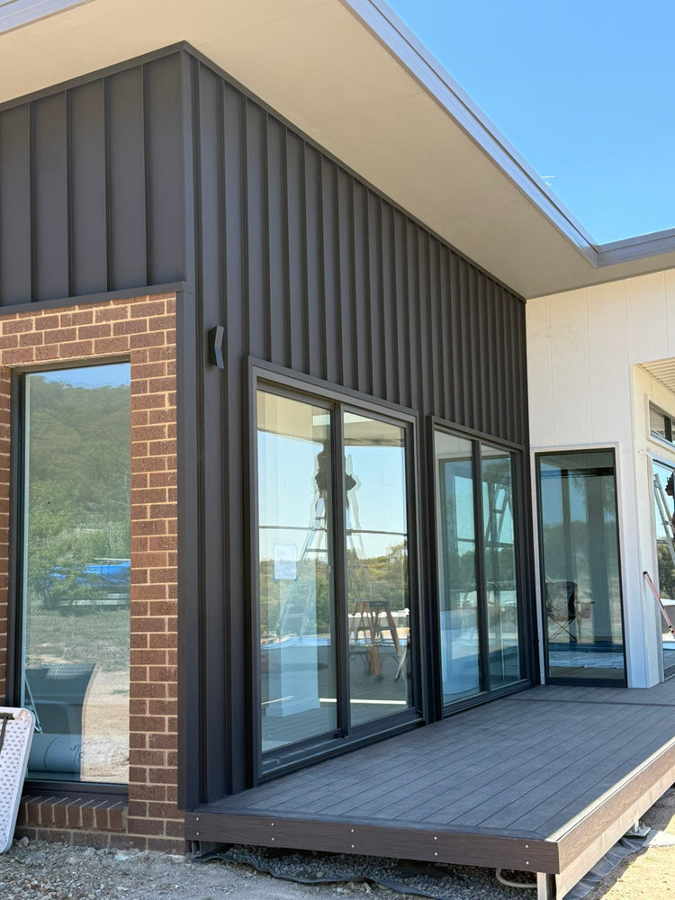 Dark standing-seam cladding over a brick home
